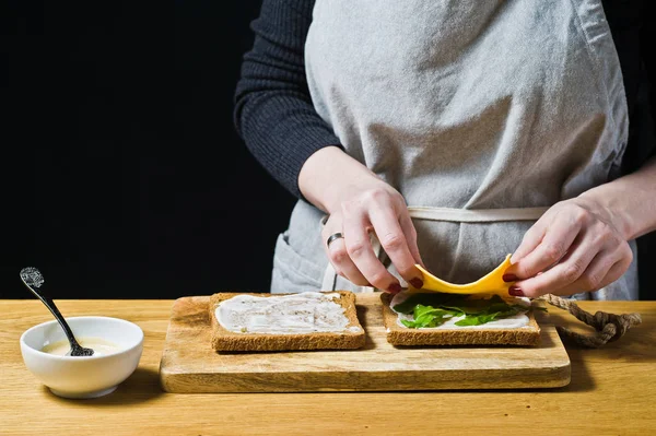 Chef Prepara Sándwich Pan Negro Pone Hojas Rúcula Tostadas Fondo — Foto de Stock