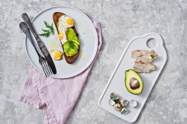 Gri bir tabak yumurta ile avokado sandviç. Gri arka plan, üstten görünüm