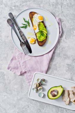 Gri bir tabak yumurta ile avokado sandviç. Gri arka plan, üstten görünüm