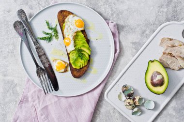 Gri bir tabak yumurta ile avokado sandviç. Gri arka plan, üstten görünüm