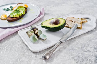 Avokado ve tost siyah ekmek üzerinde yumurta sandviç. Gri arka plan, yan görünüm