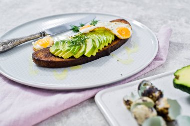 Siyah ekmek tost yumurta ile Avacado sandviç. Gri arka, yan görünüm
