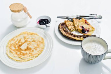 Kahvaltıda krep, böğürtlenli reçel, kızarmış muz ve kahve edilir. Beyaz arka plan, üstten görünüm, yakın çekim