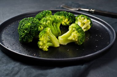 Siyah bir plaka üzerinde çiğ brokoli. Siyah arka plan, yan görünüm, yakın çekim