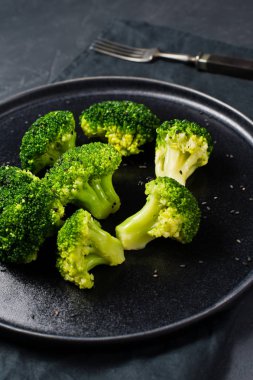 Haşlanmış brokoli siyah bir plaka üzerinde. Siyah arka plan, yan görünüm, yakın çekim