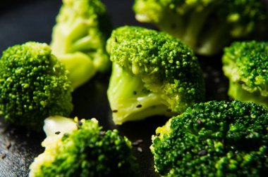 Haşlanmış brokoli siyah bir plaka üzerinde. Siyah arka plan, yan görünüm, yakın çekim