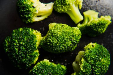 Haşlanmış brokoli siyah bir plaka üzerinde. Siyah arka plan, yan görünüm, yakın çekim