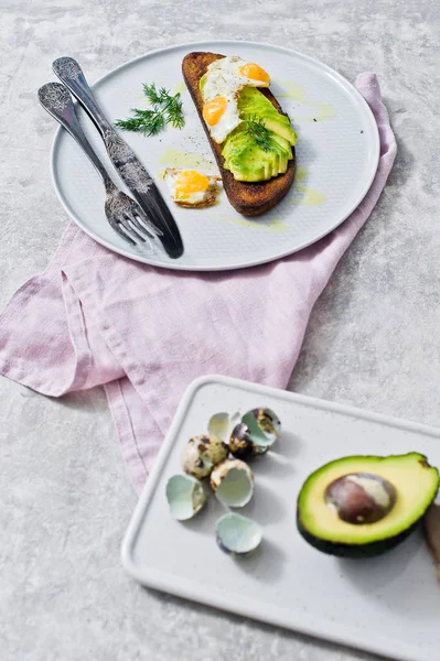 Avokado ve tost siyah ekmek üzerinde yumurta sandviç. Gri arka plan, yan görünüm