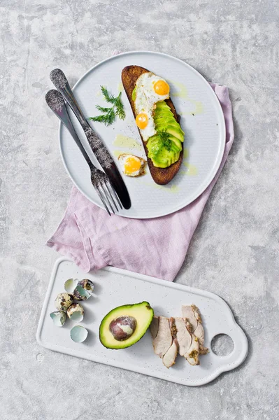 Avokado ve tost siyah ekmek üzerinde yumurta sandviç. Gri arka plan, üstten görünüm