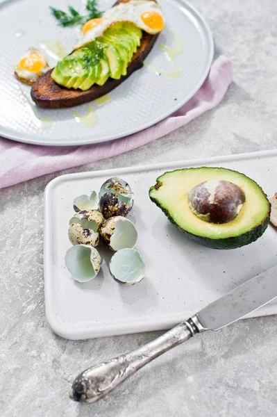 Avokado ve tost siyah ekmek üzerinde yumurta sandviç. Gri arka plan, yan görünüm