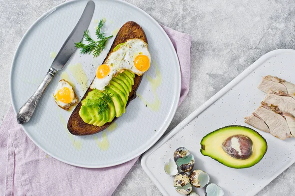 Avokado ve tost siyah ekmek üzerinde yumurta sandviç. Gri arka plan, üstten görünüm