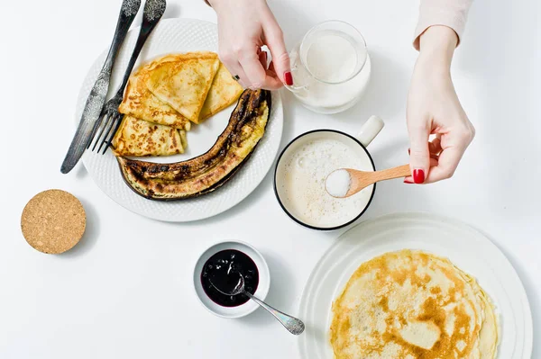 Kız bir fincan kahve, Kahvaltı krep ile bir kaşık dolusu şeker kamışı koyar. Beyaz arka plan, üstten görünüm, yakın çekim