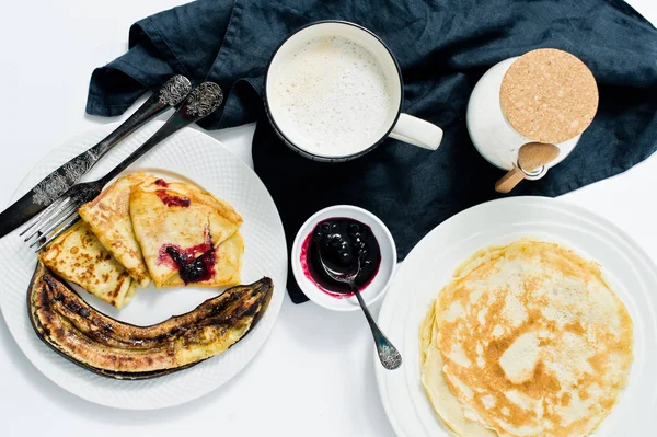Kahvaltıda krep, böğürtlenli reçel, kızarmış muz ve kahve edilir. Beyaz arka plan, üstten görünüm, yakın çekim