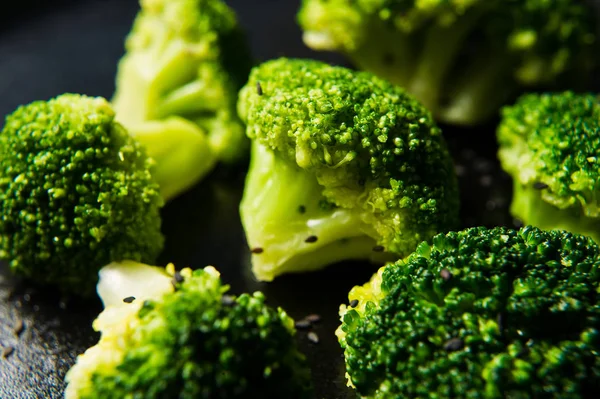 Haşlanmış brokoli siyah bir plaka üzerinde. Siyah arka plan, yan görünüm, yakın çekim