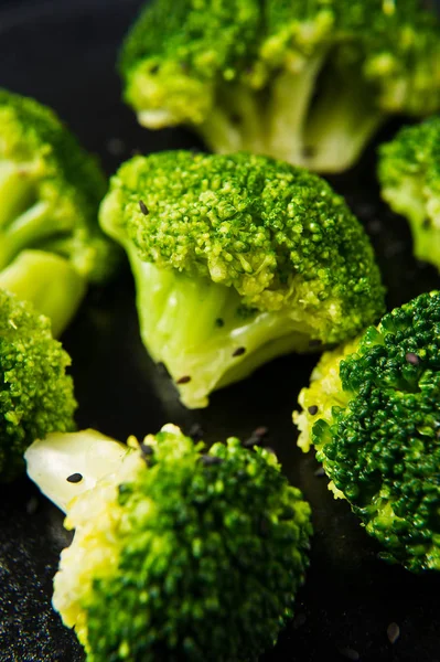 Haşlanmış brokoli siyah bir plaka üzerinde. Siyah arka plan, yan görünüm, yakın çekim