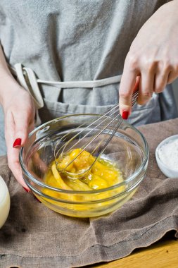 Şef bir kaseye yumurta ve şeker kamışı kamçı. Hamur işleri pişirme kavramı. Malzemeler: Bıldırcın yumurta, şeker, un, süt. Siyah arka plan, üstten görünüm, mutfak