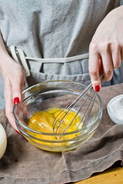 Şef, bir çırpma teli ile bir kase içine yumurta ve şeker kamışı kamçı. Gluten free yemek ve laktoz ücretsiz pişirme kavramı. Malzemeler: Bıldırcın yumurta, şeker, glutensiz un, yulaf sütü. Siyah arka plan, yan görünüm, mutfak