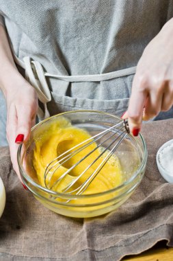 Şef bir kaseye yumurta ve şeker kamışı kamçı. Hamur işleri pişirme kavramı. Malzemeler: Bıldırcın yumurta, şeker, un, süt. Siyah arka plan, üstten görünüm, mutfak