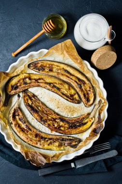 Bir pişirme çanağı bal ile kızarmış muz. Siyah arka plan, üstten görünüm, metin için yer