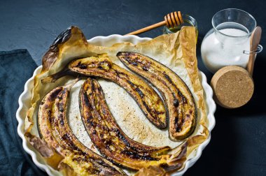 Bir pişirme çanağı bal ile kızarmış muz. Siyah arka plan, üstten görünüm, metin için yer