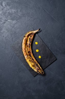 Siyah taş kurulu ballı muz pişmiş. Siyah arka plan, üstten görünüm, yakın çekim