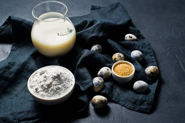 The concept of cooking gluten-free and lactose-free baking. Ingredients: bananas, quail eggs, sugar, gluten free flour, oat milk. Black background, top view