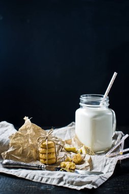 Kurabiye bisküvi, bir bardak süt. Siyah arka plan, yan görünüm, metin için yer