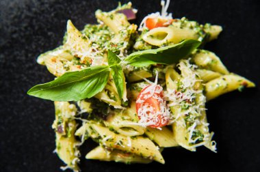 Ispanak, domates ve fesleğen ile İtalyan makarna Penne. Siyah arka plan, üstten görünüm, yakın çekim