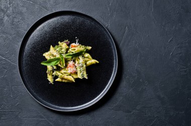 Ispanak, domates ve fesleğen ile İtalyan makarna Penne. Siyah arka plan, üstten görünüm, metin için yer