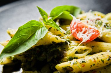 Ispanak, domates ve fesleğen ile İtalyan makarna Penne. Siyah arka plan, üstten görünüm, yakın çekim