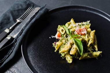 Ispanak, domates ve fesleğen ile İtalyan makarna Penne. Siyah arka plan, yan görünüm, yakın çekim