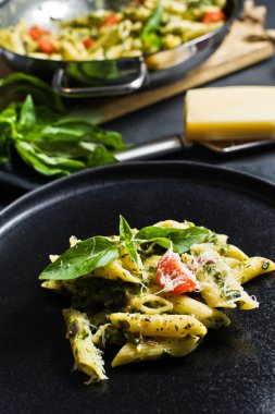 Ispanak, domates ve fesleğen ile İtalyan makarna Penne. Siyah arka plan, yan görünüm