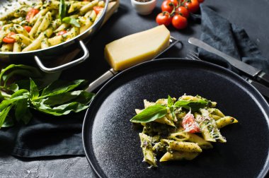 Ispanak, domates ve fesleğen ile İtalyan makarna Penne. Siyah arka plan, yan görünüm