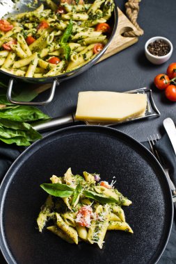 Ispanak, domates ve fesleğen ile İtalyan makarna Penne. Siyah arka plan, yan görünüm