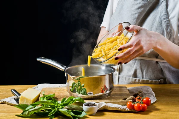 Chef Versa Pasta Penne Una Pentola Acqua Bollente Sfondo Nero — Foto Stock