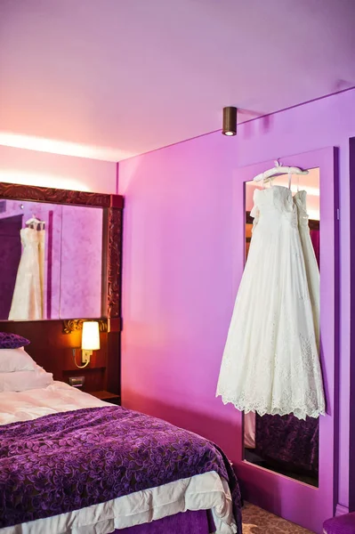 White bridesmaid dress in the interior of the hotel, purple background