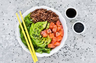 Somon salata, avokado, kahverengi pirinç, deniz yosunu. Gri arka plan, yan görünüm, metin için yer