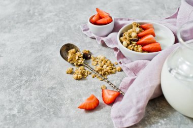 Kahvaltı organik ev yapımı granola kase çilek ve yoğurt içerir. Gri arka plan, üstten görünüm. Dengeli beslenme