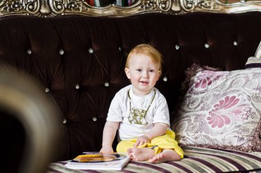 Kanepede oturan ve bir kitap Kızıl saçlı bebek