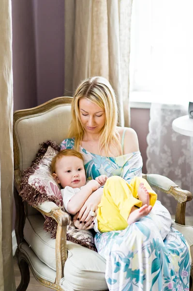 Mom and baby sit in an old chair and play