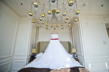 Gelinin avize otel odasında asılı beyaz gelinlik
