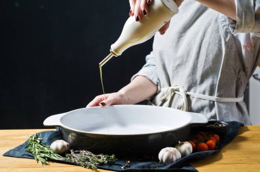 Şef zeytinyağı bir pişirme çanağı dökülen. Siyah arka plan, yan bakış, metin için yer mutfak