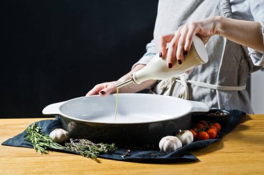 Şef zeytinyağı bir pişirme çanağı dökülen. Siyah arka plan, yan bakış, metin için yer mutfak