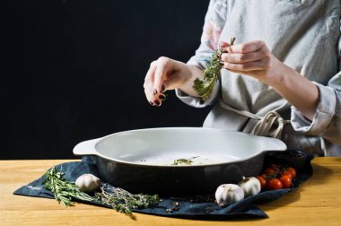 Şef pişirme çanağı biberiye ekler. Fırında patates pişirme kavramı. Siyah arka plan, yan bakış, metin için yer mutfak