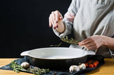 Şef pişirme çanağı biberiye ekler. Fırında patates pişirme kavramı. Siyah arka plan, yan bakış, metin için yer mutfak