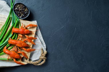 Ahşap doğrama tahtası üzerinde pişmiş kerevit. Siyah arka plan, üstten görünüm, metin için yer.