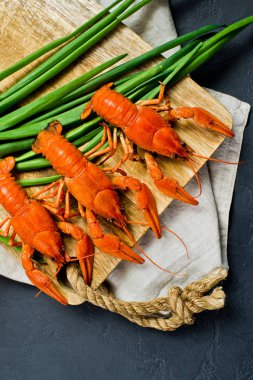 Ahşap doğrama tahtası üzerinde pişmiş Kızılırmak kerevit. Siyah arka plan, üstten görünüm.