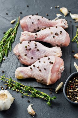 Tavuk bacağı çeyrek. Yemek pişirmek için malzemeler: biberiye, kekik, sarımsak, biber. Siyah arka plan, yan görünüm.