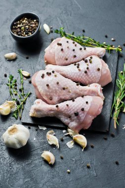 Tavuk bacağı çeyrek. Yemek pişirmek için malzemeler: biberiye, kekik, sarımsak, biber. Siyah arka plan, yan görünüm.