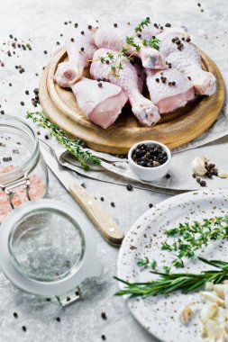 Tavuk bacağı çeyrek. Yemek pişirmek için malzemeler: biberiye, kekik, sarımsak, biber. Gri arka, yan görünüm.